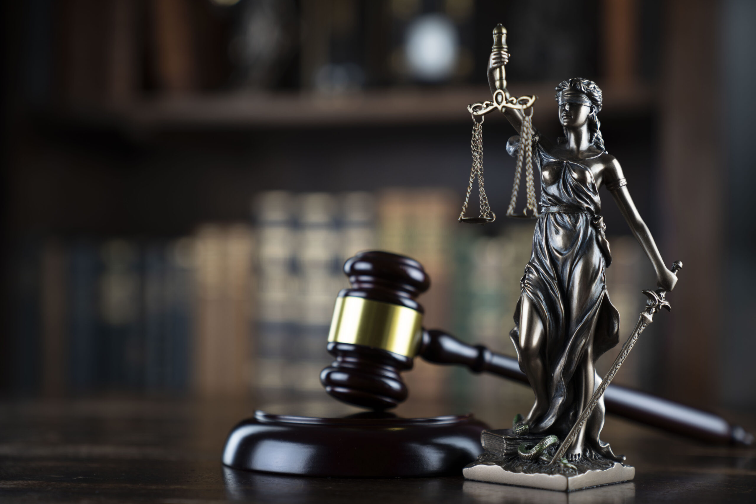 Law symbols composition: judge’s gavel, Themis sculpture and legal books.